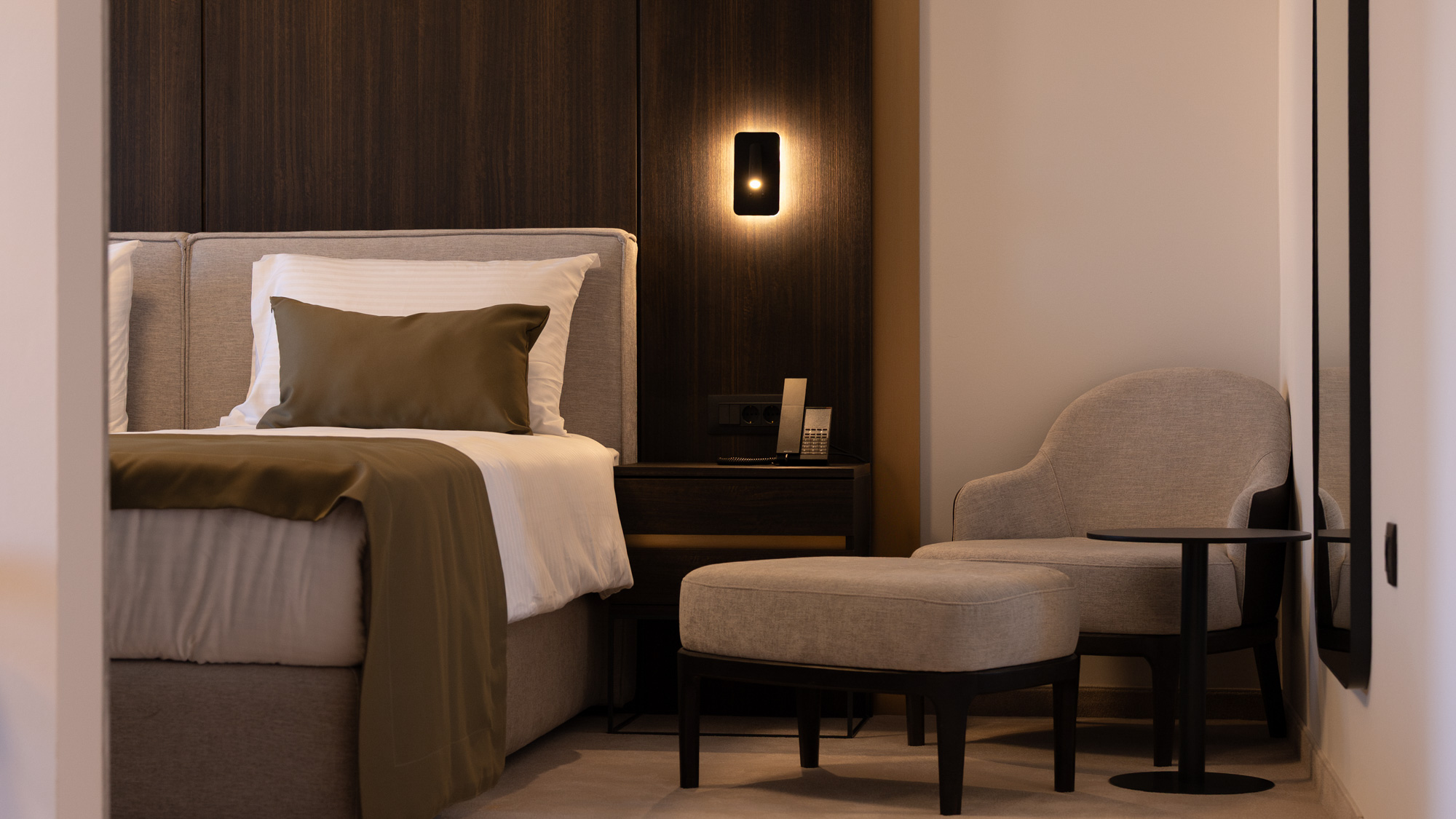 Room overview — bed, sconce, and armchair