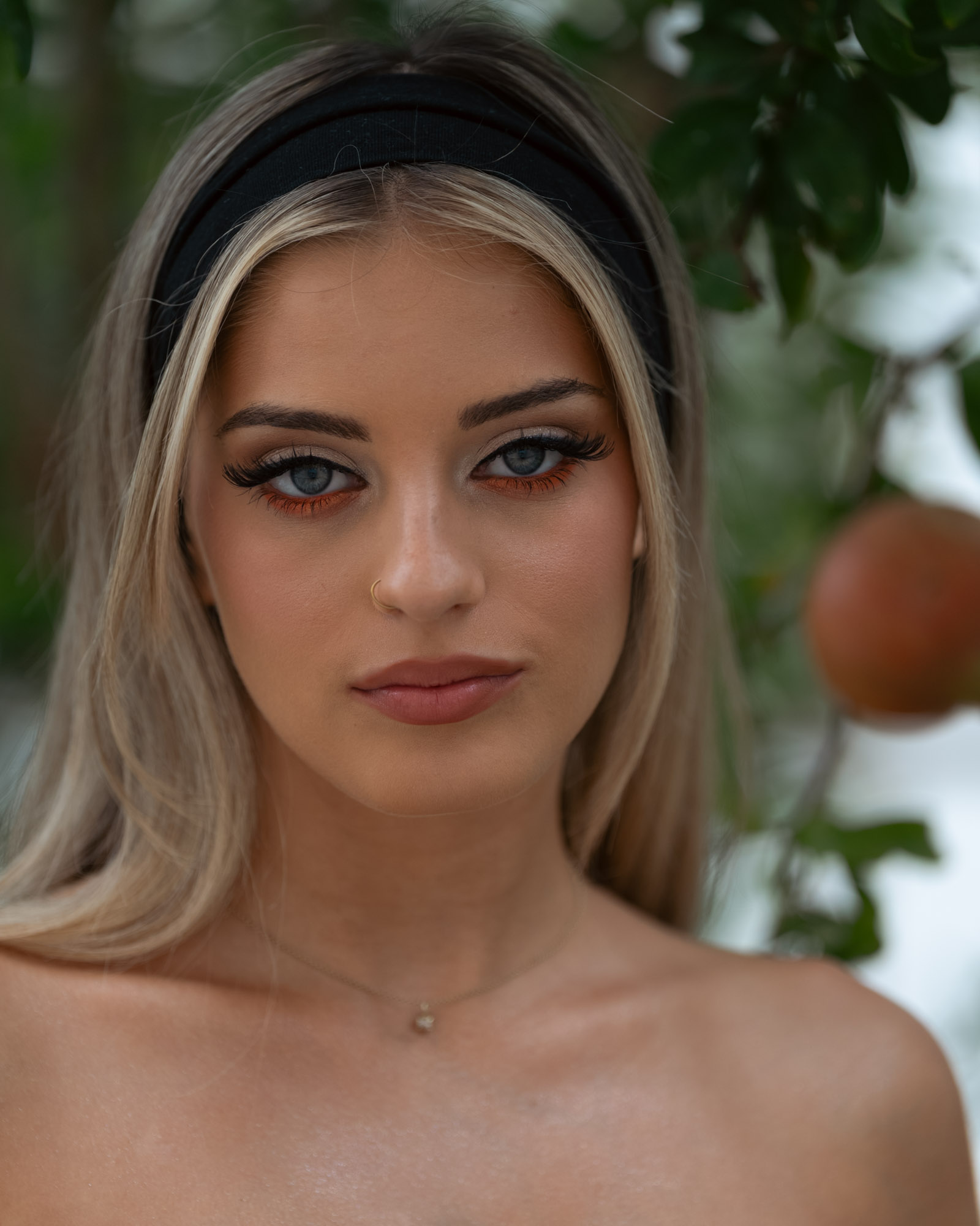 Close portrait, eyes to camera, pomegranate soft in the background