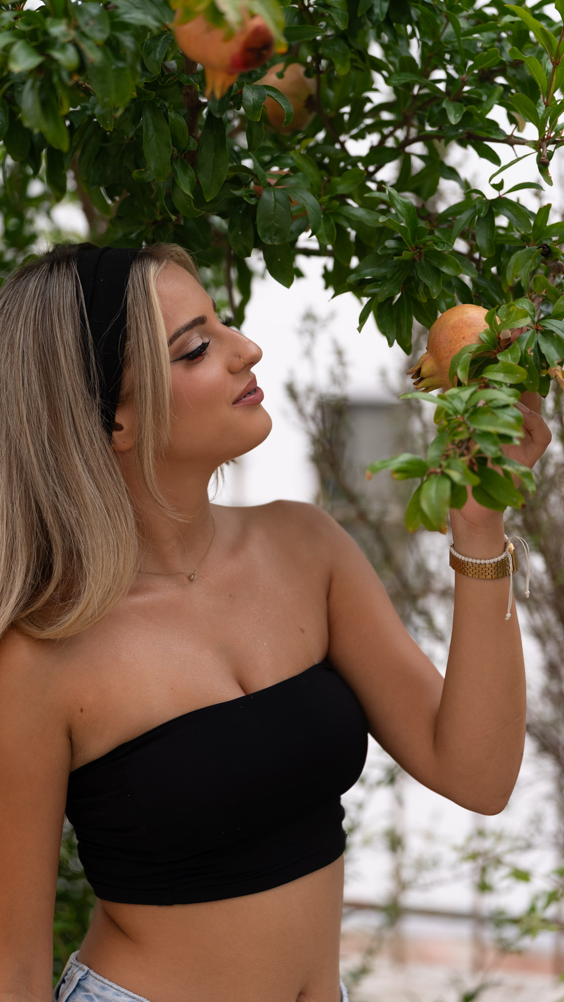 Portrait in profile reaching up to a pomegranate branch