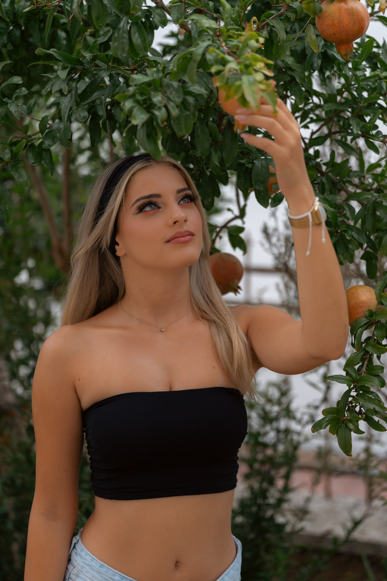 Arm raised to the fruit, gaze off-frame
