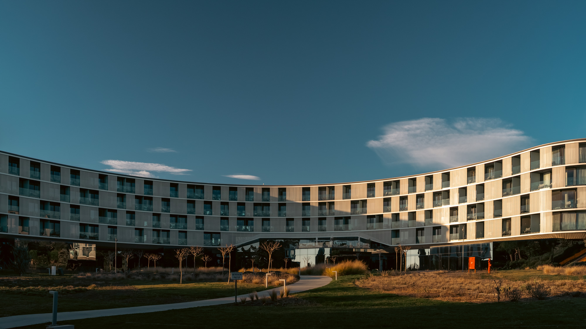 Wide view of Amarin's curved hotel facade against a clear sky