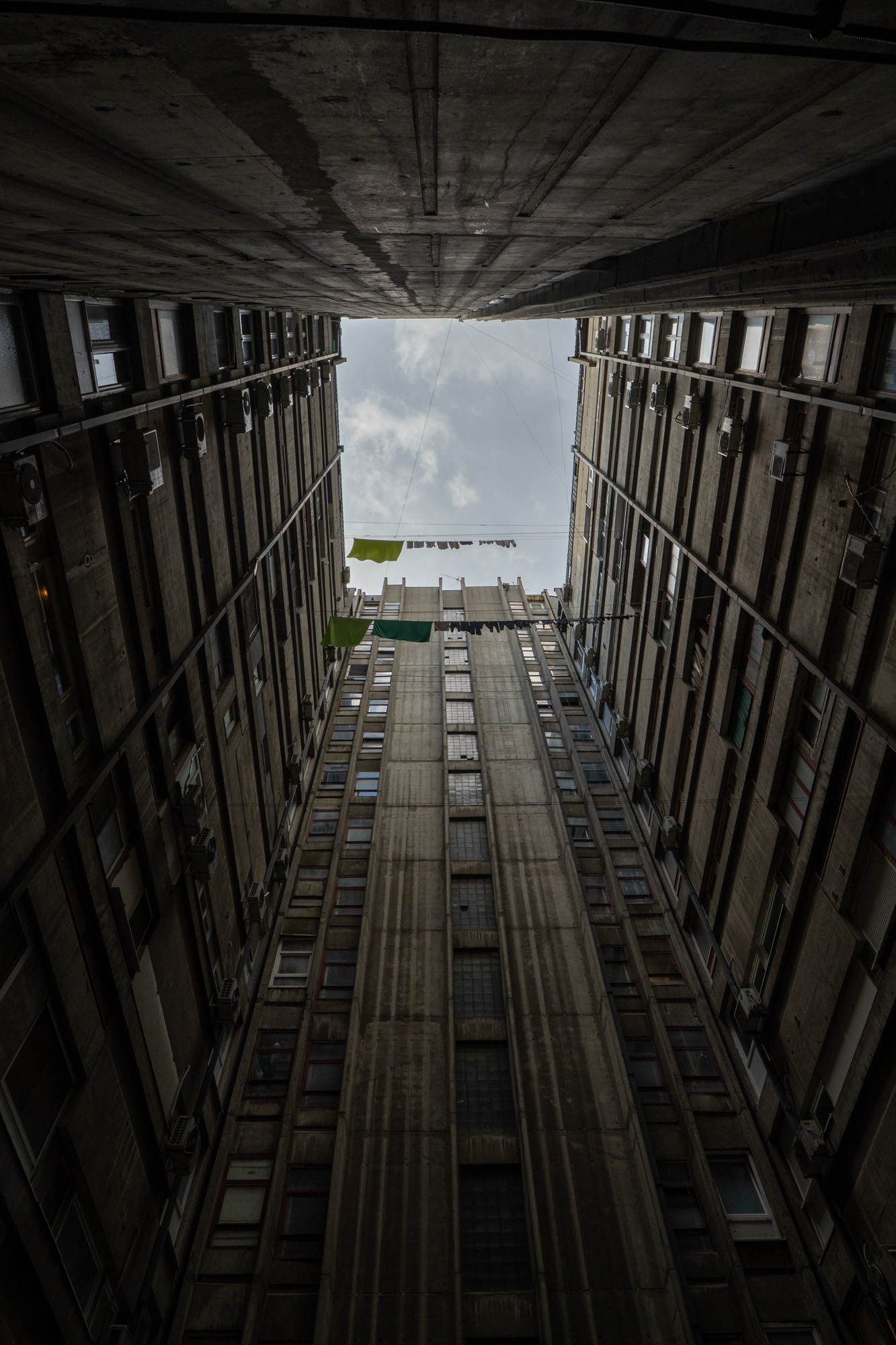 Looking up through a brutalist Belgrade courtyard, laundry strung between floors