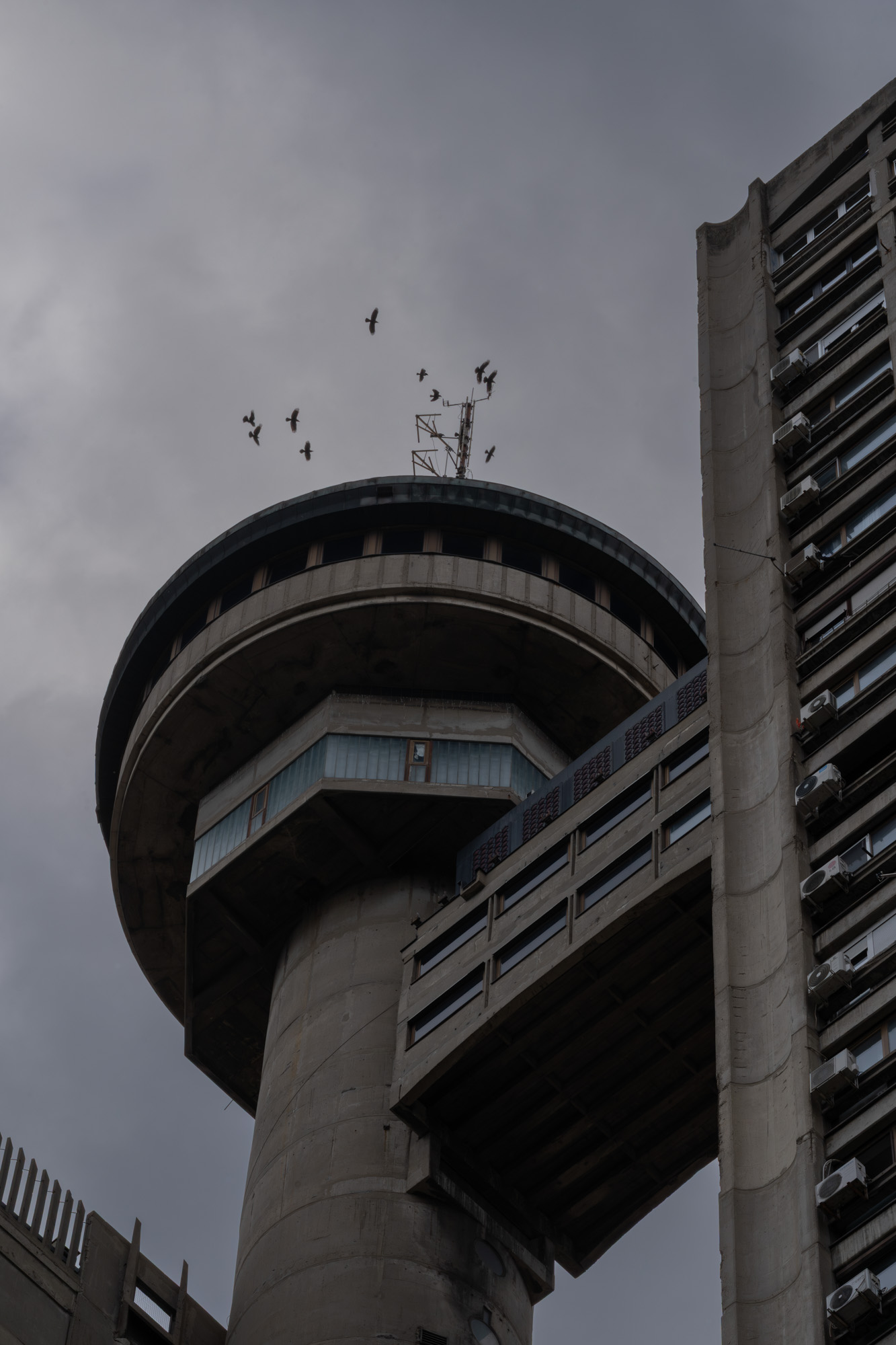 Genex Tower circular top with birds in flight, adjacent residential slab tower, Belgrade