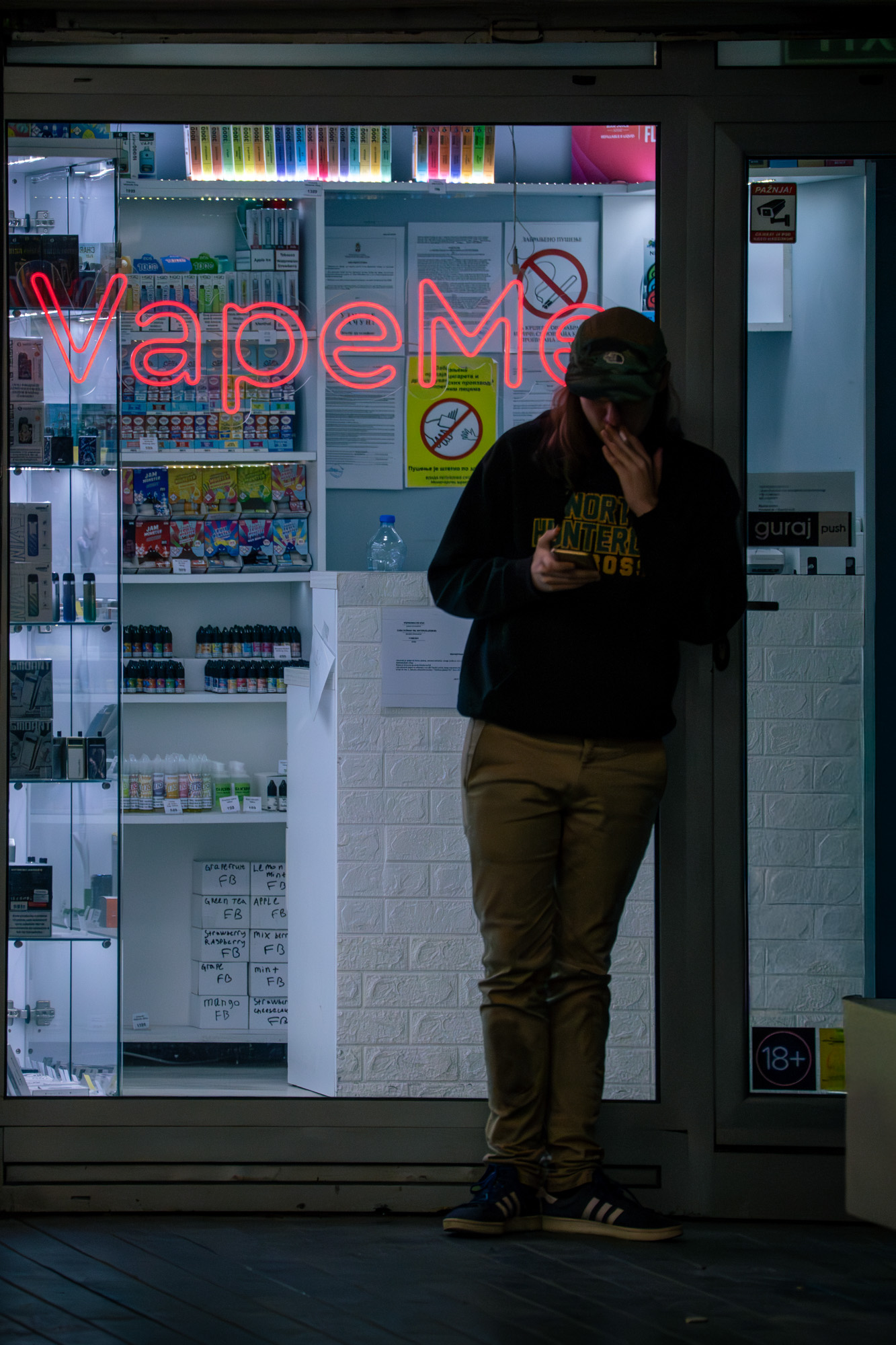 Person at a vape shop doorway, Belgrade at night